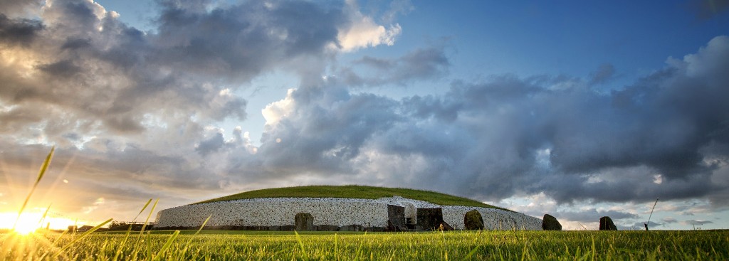 Newgrange passage tomb in the Boyne Valley lit by a low sun over green fields
